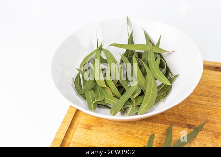 Vista di una piastra bianca con foglie di eucalipto essiccate un tagliere di legno Foto Stock