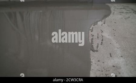 Versare il pavimento liquido sulla superficie in calcestruzzo. Livellare il pavimento con una Malta autolivellante. Livellare il pavimento con una Malta autolivellante. Foto Stock