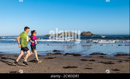 East Lothian, Scozia, Regno Unito, 27 settembre 2020. Scurry running event: I runner prendono parte a un divertente evento di corsa dalla spiaggia di Yellowcraig a North Berwick e ritornano in una bella e soleggiata mattinata d'autunno. L'isola di Fidra è sullo sfondo come una corsa di coppia sulla spiaggia Foto Stock