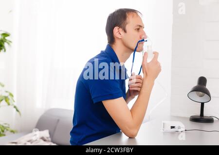 Ritratto di giovane uomo inalazione attraverso inalatore maschera Foto Stock