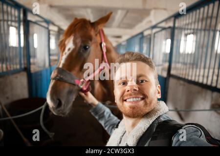 Horseman si prepara a cavalcare il cavallo attraverso l'ippodromo Foto Stock