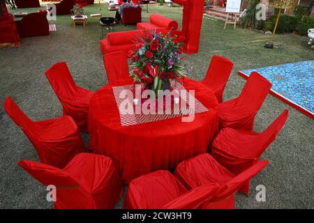 Tavolo rosso organizzato e sedie decorate con fiore centerpiece, disposizione seduta di lusso pronto per gli ospiti su una prateria o cortile Foto Stock