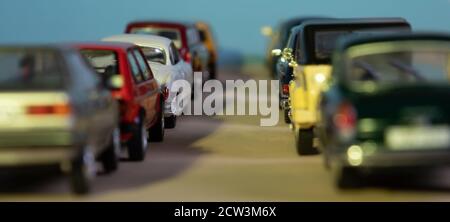 Guardando attraverso due file di auto giocattolo, simbolo di inizio traffico e ingorgo, concentrarsi su una macchina, sfondo blu Foto Stock