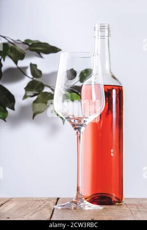 Bicchiere di vino rosato con bottiglia sul tavolo bianco. Rosado, rosato o degustazione di vini arrossati in wineshop, concetto bar. Copia spazio Foto Stock