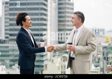 Imprenditori sorridenti che scuotono le mani Foto Stock