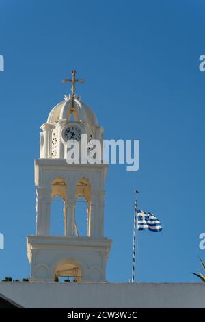 Particolare tipico di un campanile di una chiesa ortodossa bianca nel villaggio di megalochori, santorini, cicladi, grecia. Bandiera greca nel cielo blu Foto Stock
