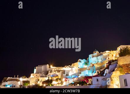 Notte che cade sul villaggio greco di Oia sull'isola di Santorini. Tipica chiesa ortodossa sovrasta il villaggio. Bel cielo con stelle Foto Stock