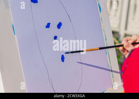 Luogo di lavoro dell'artista. Un capretto dipinge con gouache blu un'immagine. Officina all'aperto Foto Stock