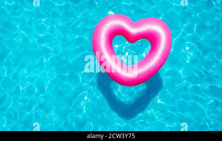 Buoi gonfiabili con cuore di rose nuotano nella vista della piscina dall'alto Foto Stock