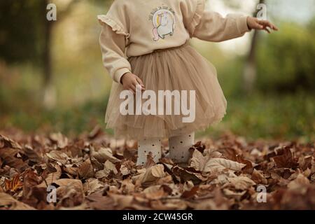 Carino elegante bambina a piedi nel parco autunnale. Moda bambini autunno. Felice infanzia. Ritratto stile di vita. Bambino caucasico 6 anni all'aperto Foto Stock