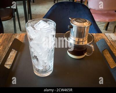 Cafe sua da, caffè ghiacciato vietnamita con latte condensato zuccherato. Utilizzo di caffè arrosto scuro macinato grossolano con filtro antigoccia in metallo. Foto Stock