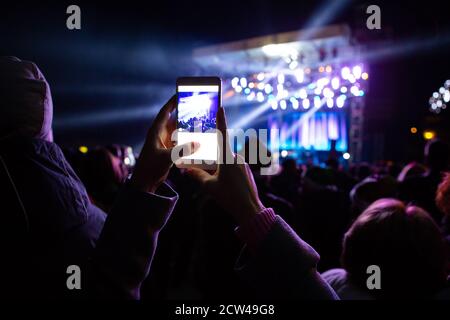 Una ragazza sta scattando le foto di un concerto di strada sopra il telefono Foto Stock