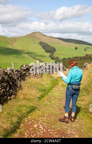 Donna che legge mappa a piedi verso il Cheshire mini montagna Shutlingsloe Nel distretto di Peak Inghilterra Regno Unito Foto Stock