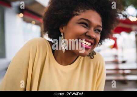 Primo piano di una bella donna afro-americana latina sorridente e trascorrere del tempo piacevole alla caffetteria. Foto Stock