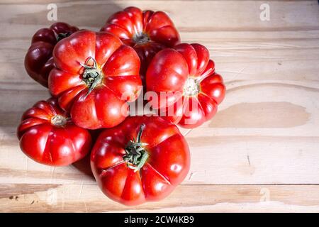 Prodotti siciliani: Tipico pomodoro Corleone di riccia detto 'siccagno'. Gruppo di pomodori posti a sinistra su superficie di legno Foto Stock