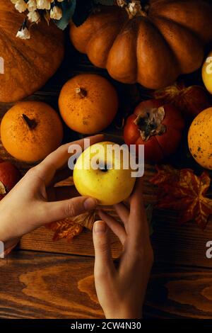 Sfondo di zucche, mele e persimmons. Vendemmia autunnale su un tavolo di legno. Verdure e frutta nelle tue mani. Il concetto di ringraziamento, festival della raccolta. Foto Stock