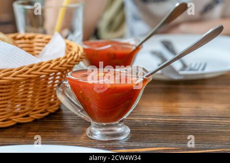 Salsa di pomodoro in un piatto di vetro trasparente su un legno primo piano del tavolo Foto Stock