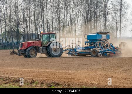 Piccola azienda agricola con trattore rosso e aratri in un campo Foto Stock