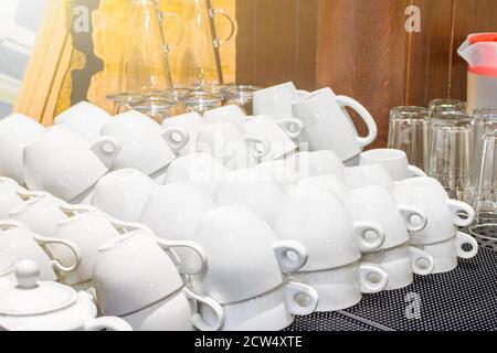 Molte tazze bianche bianche e pulite si trovano sulla gomma tappetino nel ristorante dopo il lavaggio Foto Stock