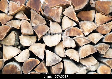 Legna da ardere secca accatastata sotto il muro. Sfondo di tronchi di legna da ardere tagliata a secco in un palo. Texture ravvicinata Foto Stock