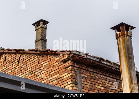 vecchia canna fumaria di amianto pericoloso su tetto di tegole di sbriciolamento casa Foto Stock