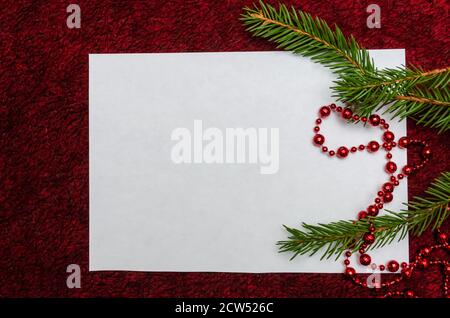 Foglio bianco di carta giace su uno sfondo morbido Borgogna con decorazioni natalizie. Sfondo di Natale con spazio di copia Foto Stock