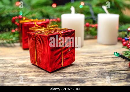 Scena natalizia con candele bianche, mini regali rossi, rami di abete e ghirlanda su sfondo di legno con spazio copia. Bellissimo sfondo di Natale Foto Stock