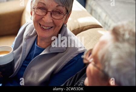 La coppia anziana si rilassa e chiacchiera insieme sul divano a casa Con bevanda calda Foto Stock