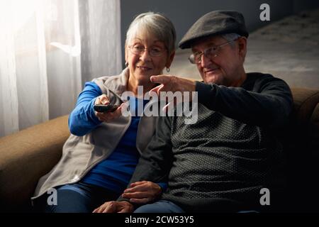 Coppia senior amorevole seduta sul divano a casa guardando la televisione Insieme Foto Stock