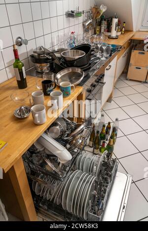 Cucina dopo una cena più grande, festa di cottura, lavastoviglie, completa, con piatti puliti, bicchieri sporchi, pentole, utensili da cucina sul lavandino, in attesa di essere Foto Stock