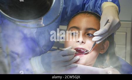 Giovane caucasica che si prende cura dei suoi denti. Ritratto di affascinante ragazza seduta in sedia dentista. Foto Stock