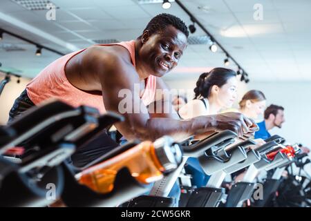 L'uomo africano e gli amici sul fitness bike in palestra Foto Stock