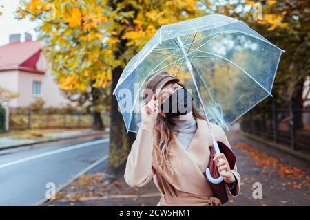 Donna con un ombrello a piedi lungo la strada in un giorno di pioggia Foto  stock - Alamy