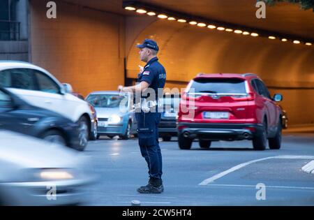 Belgrado, Serbia - 25 settembre 2020: Poliziotto in servizio, in piedi all'incrocio con il traffico in movimento sfocato Foto Stock