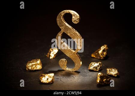 Il segno del paragrafo d'oro e i nocciole d'oro su sfondo nero. Foto Stock