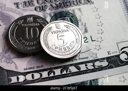 Monete ucraine hryvnia piazzate su banconote in dollari. Nuovo tipo di monete rilasciate nel 2019 sostituire banconote in carta. Concetto di cambio valuta. Foto Stock