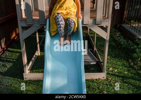 Bambino seduto sulla parte superiore di uno scivolo blu Foto Stock