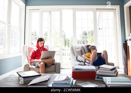 Tween su laptop, Grade School Brother su tablet, lavoro su lavoro a casa Foto Stock