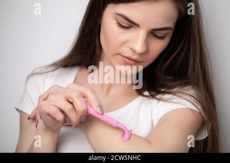 Una donna usa il rasoio per rimuovere i capelli Foto Stock