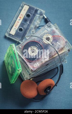 Vecchia pila di cassette audio con cuffie arancioni su blu divano Foto Stock