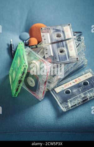 Antica pila di audiocassette con cuffie arancioni su blu divano Foto Stock