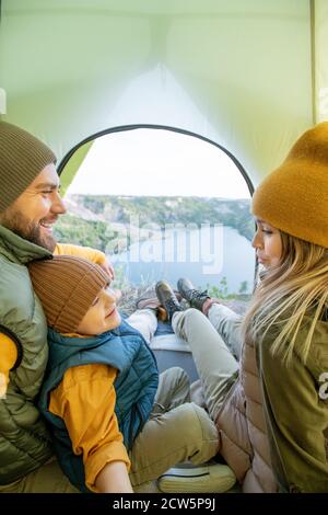 Giovane donna che parla con il bambino seduto da padre mentre la famiglia che riposa Foto Stock