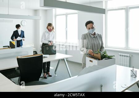 Giovani uomini d'affari in abbigliamento da formalwear e maschere di protezione che si prendono fuori materiali di consumo Foto Stock