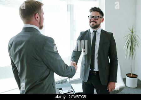 Uomo d'affari di successo maturo in formalwear guardando il suo partner commerciale Foto Stock