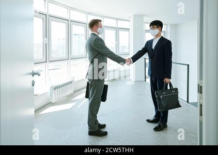 Due giovani imprenditori interculturali di successo che scuotono le mani nel corridoio Foto Stock