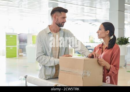 Vita in su ritratto di coppia adulta guardando l'un l'altro mentre imballando scatole di cartone in deposito o servizio di spedizione, spazio di copia Foto Stock