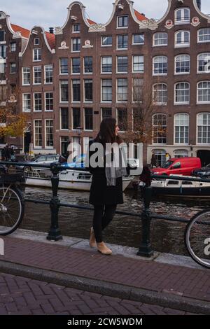 Una giovane donna di fronte ad un canale ad Amsterdam Foto Stock