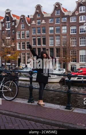 Una giovane donna di fronte ad un canale ad Amsterdam Foto Stock