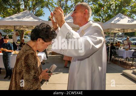 Dopo la messa, il diacono di una chiesa cattolica della California del Sud dà la sua benedizione ad un parishioner asiatico americano nel cortile esterno della chiesa. Foto Stock