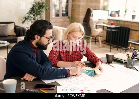 Maturo designer femminile e il suo collega di sesso maschile bearded che punta a. tavolozza dei colori Foto Stock